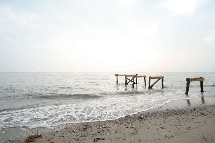 Broken wooden pier on a sandy beach by the ocean