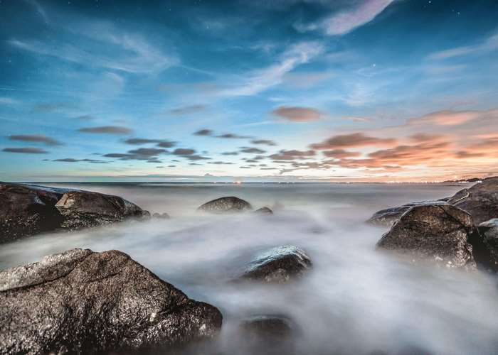 Long exposure of ocean waves crashing on rocks at dusk