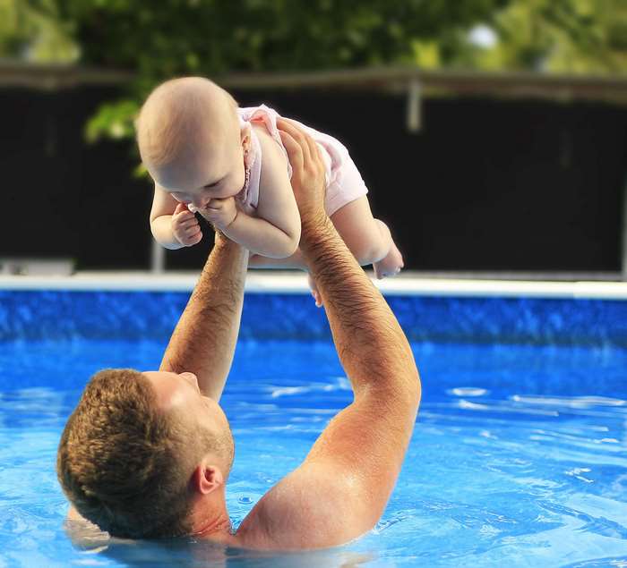 Father holding baby in swimming pool
