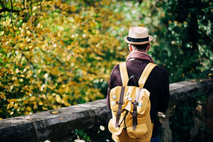 Man with backpack and hat in park during fall