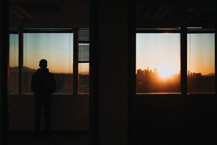 Silhouette of a person looking out a window at sunrise in Los Angeles