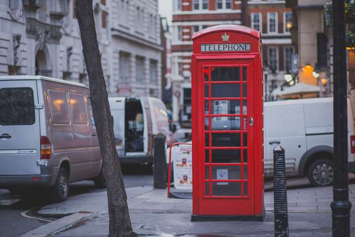 Red telephone booth on a street with panel vans