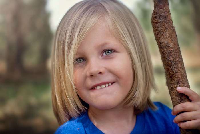 Young boy with blonde hair holding a stick
