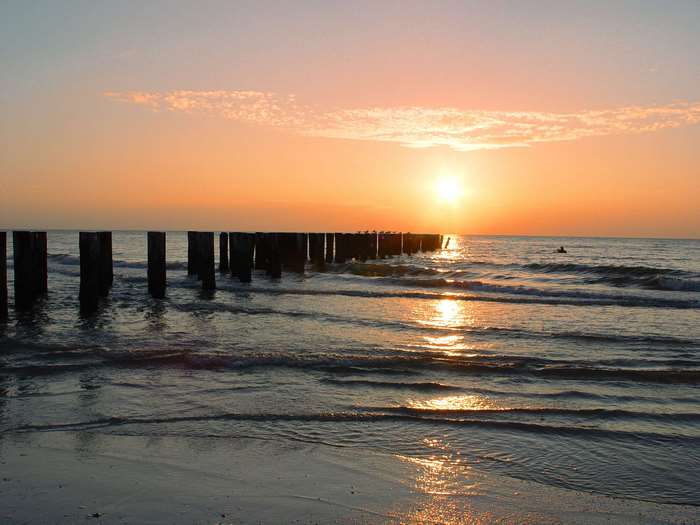 Sunset over the ocean with wooden posts