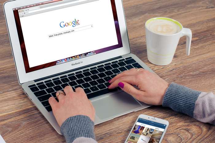 Person using MacBook Air with Google search and iPhone