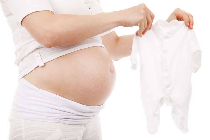 Pregnant Woman Holding White Baby Clothes 4K