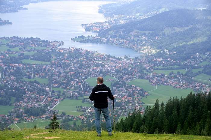 Man with hiking poles overlooking Tegernsee lake and town