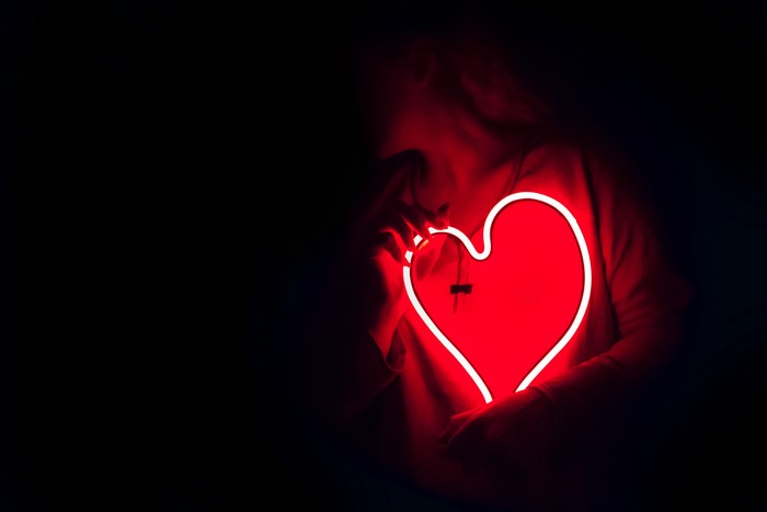 Woman holding a glowing red neon heart