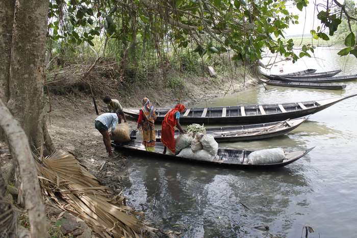 People loading goods onto boats on a river in Bangladesh