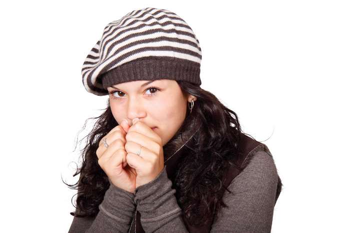 Young woman wearing a striped beanie and brown vest