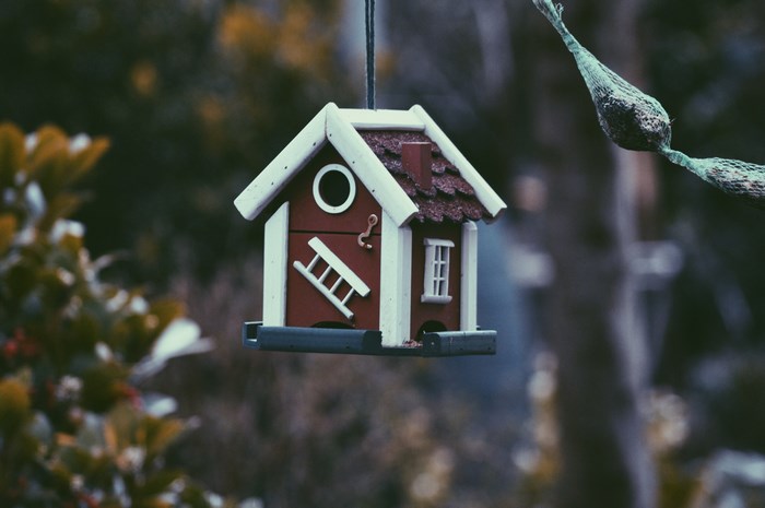 A hanging birdhouse with a ladder and window