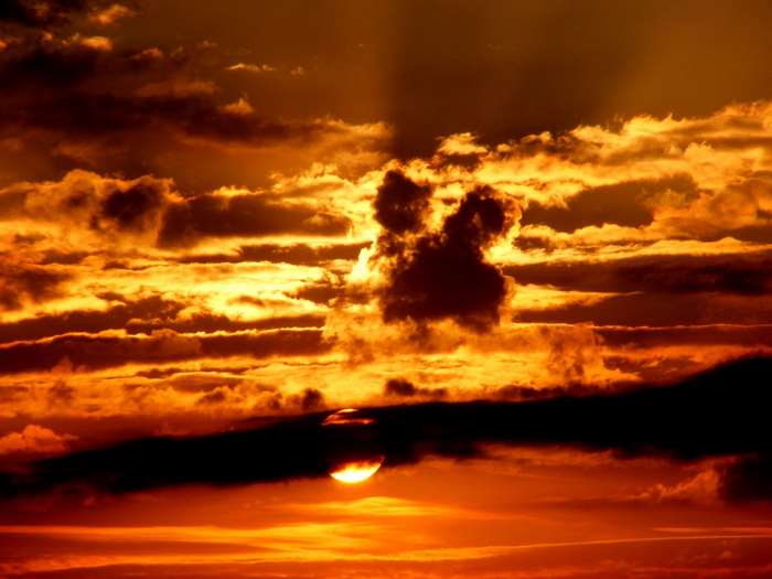 Dramatic sunset with fiery clouds and sun peeking through