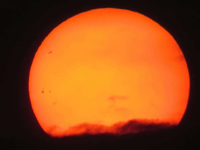 Sun with sunspots and clouds at sunset