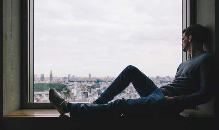 Man sitting on window sill overlooking Tokyo, Japan
