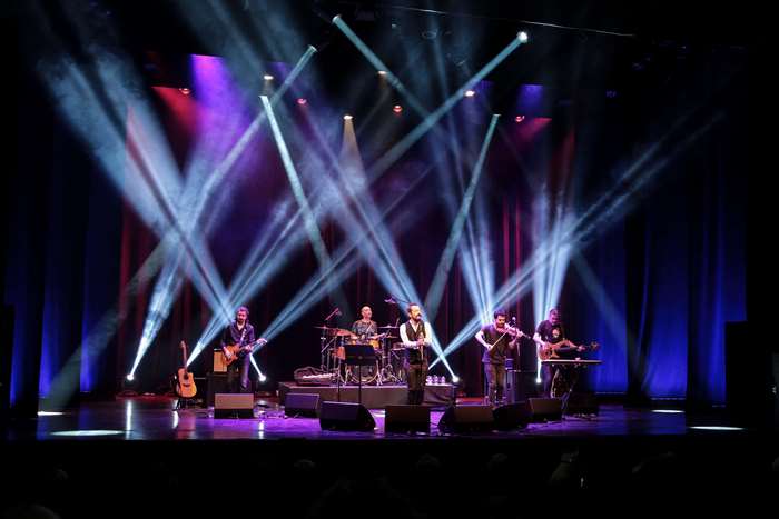 Band performing music on stage with lights