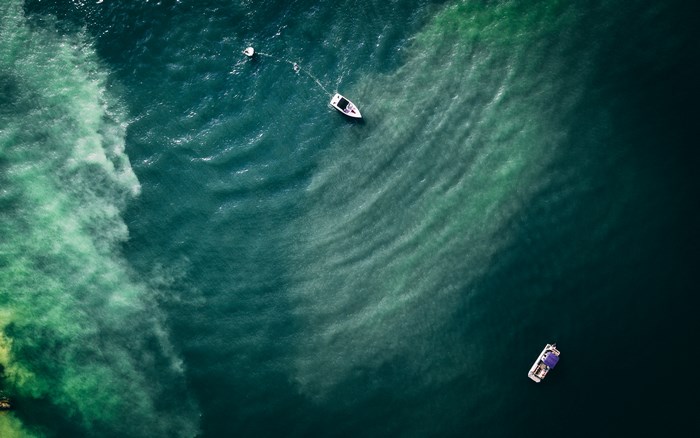 Aerial view of boats on a dark green ocean with ripples