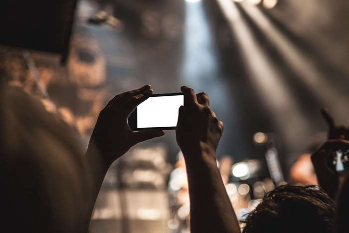 Person filming concert with smartphone