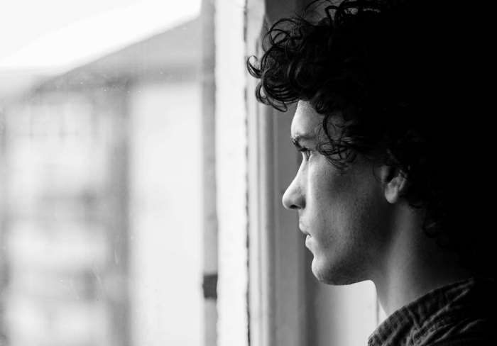 Black and white portrait of a man looking out a window