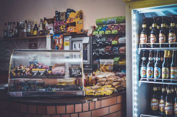Corner store counter with candy, snacks, and refrigerated beers