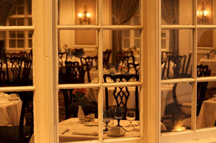 Restaurant interior with tables and chairs seen through a window