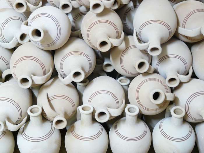 Pile of unglazed ceramic jugs with decorative rings