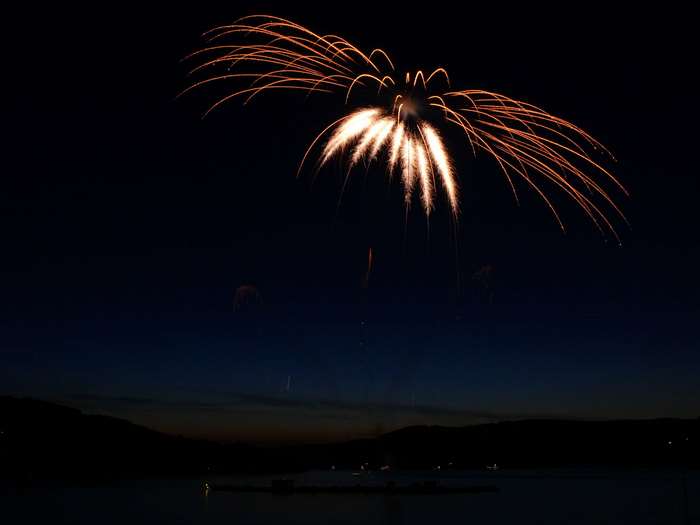 Fireworks exploding in the night sky over water