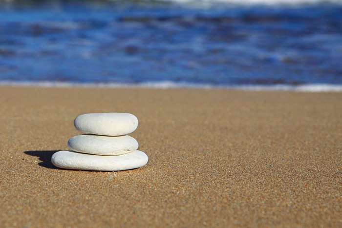 Stack of white stones on a sandy beach with ocean waves