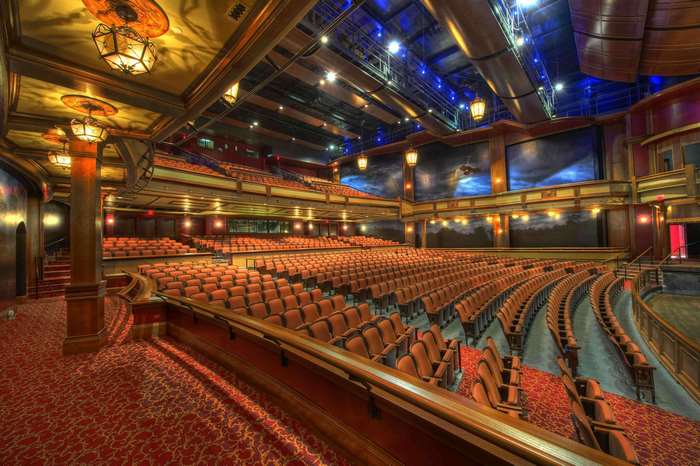 Empty theater auditorium with red carpet and ornate lighting