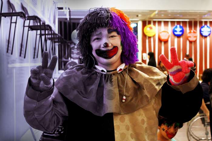 Clown with purple and orange wig making peace signs 4K