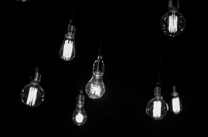Several incandescent light bulbs hanging in darkness