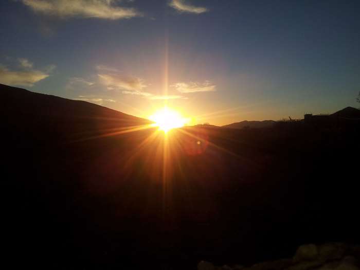 Sunset over dark mountains with sunburst