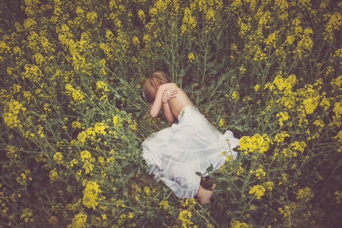 Girl sleeping in a field of yellow flowers