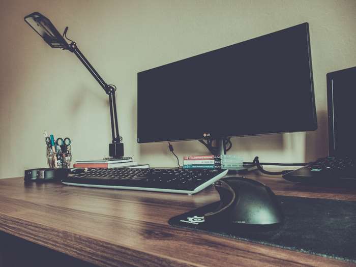 Desk with computer monitor, keyboard, mouse, and lamp