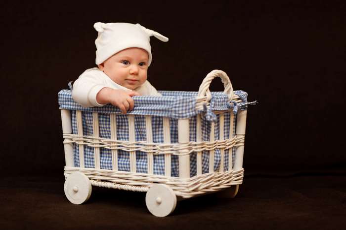 Baby in a wicker basket with a blue checkered lining