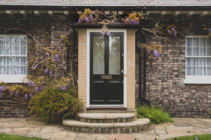 Brick house with wisteria and a black front door
