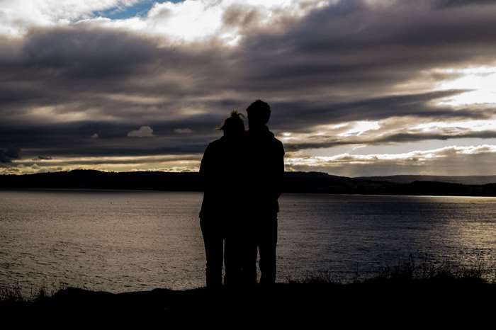 Couple silhouette by the water at sunset 4K