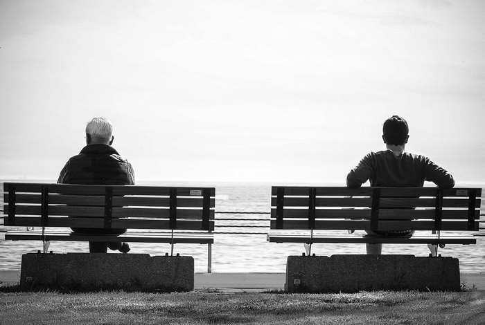 Two people sitting on benches by the water