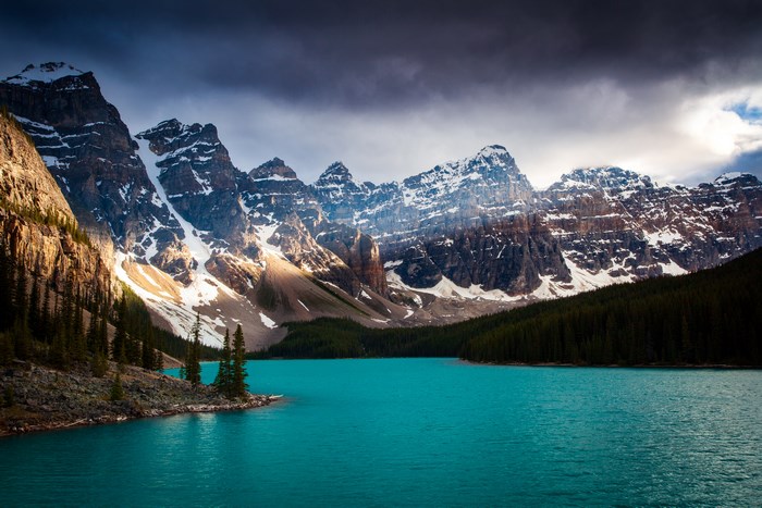 Turquoise lake and snow-capped mountains under a cloudy sky