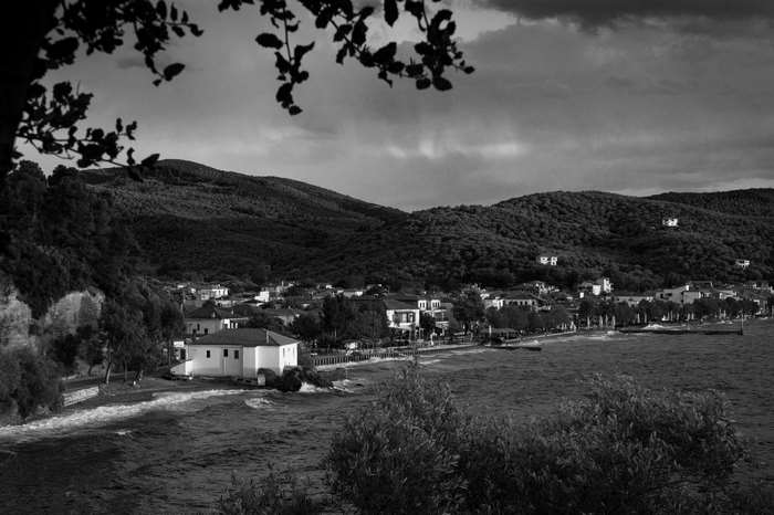 Village by the sea with mountains and dark clouds