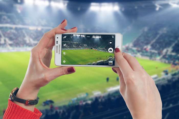 Hands holding Samsung smartphone at a football game