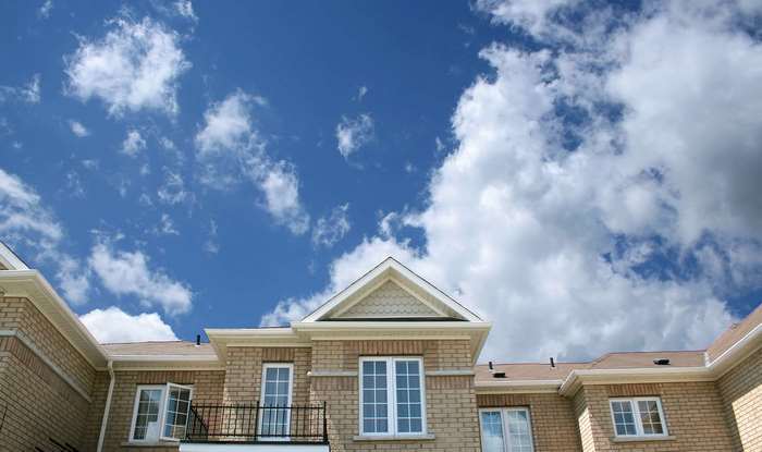 Brick building with white trim and blue sky with clouds