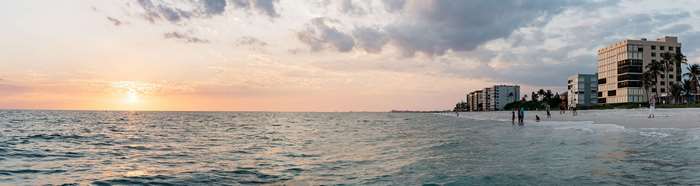 Panoramic beach sunset with ocean and buildings