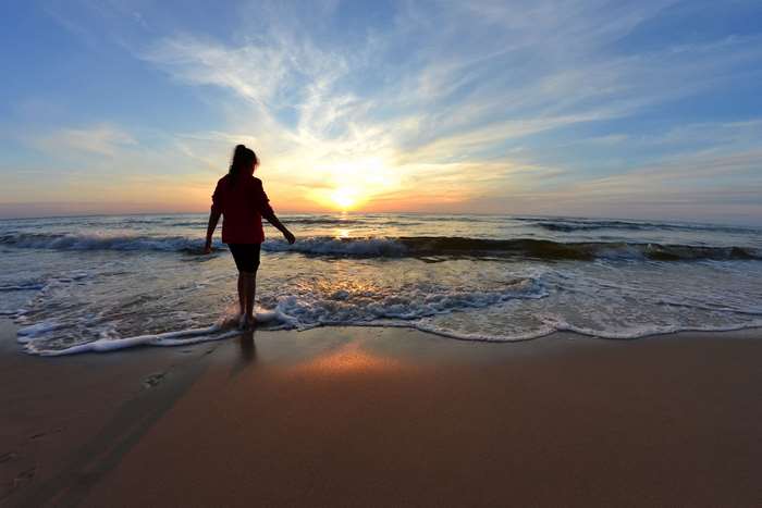 Woman walking on beach at sunset 4K