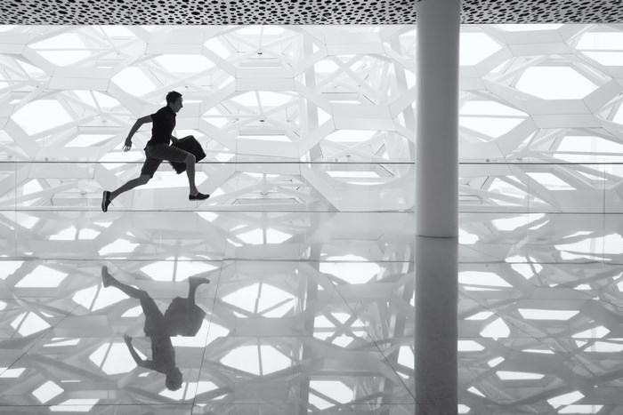 Man running with luggage in modern architecture