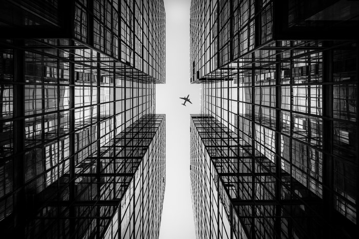 Airplane flying between Hong Kong skyscrapers