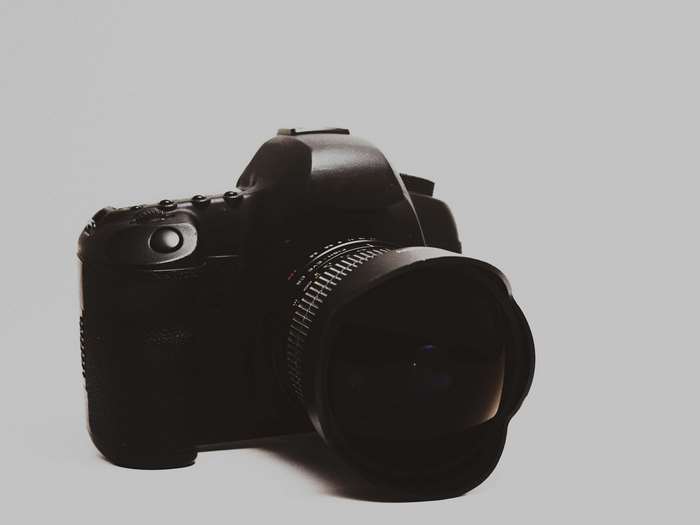 Black DSLR camera with lens on white background
