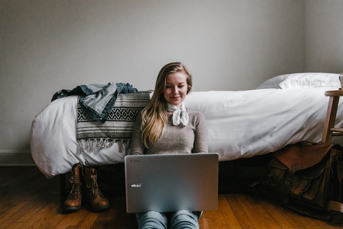 Woman using Google Chromebook on the floor by a bed