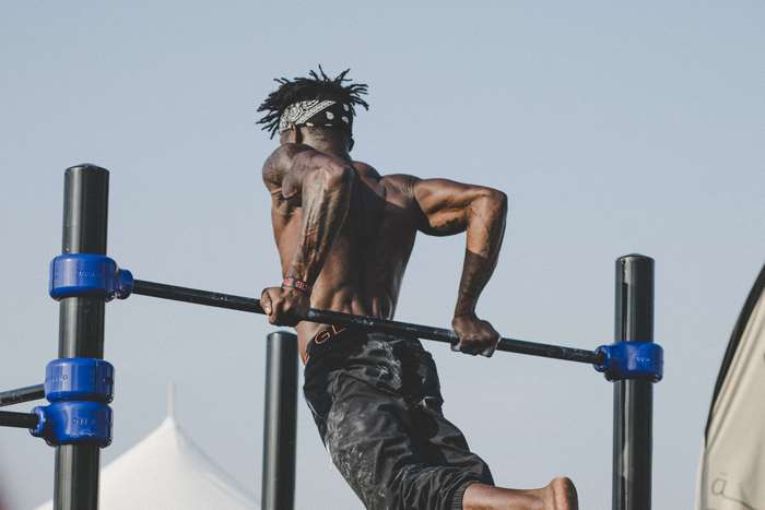 Muscular man doing dips on a pull-up bar outdoors