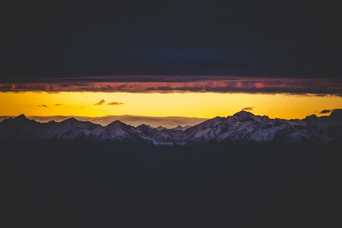 Dark Mountain Range Under a Yellow Sunset Sky