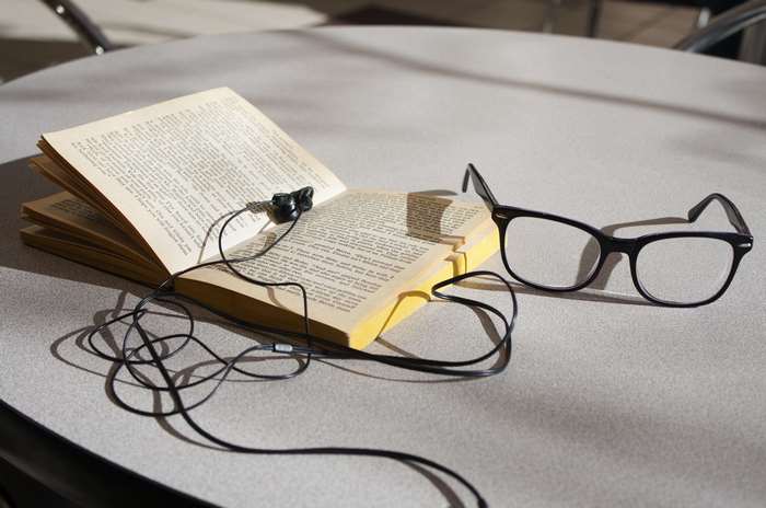 Book with headphones and glasses on a table